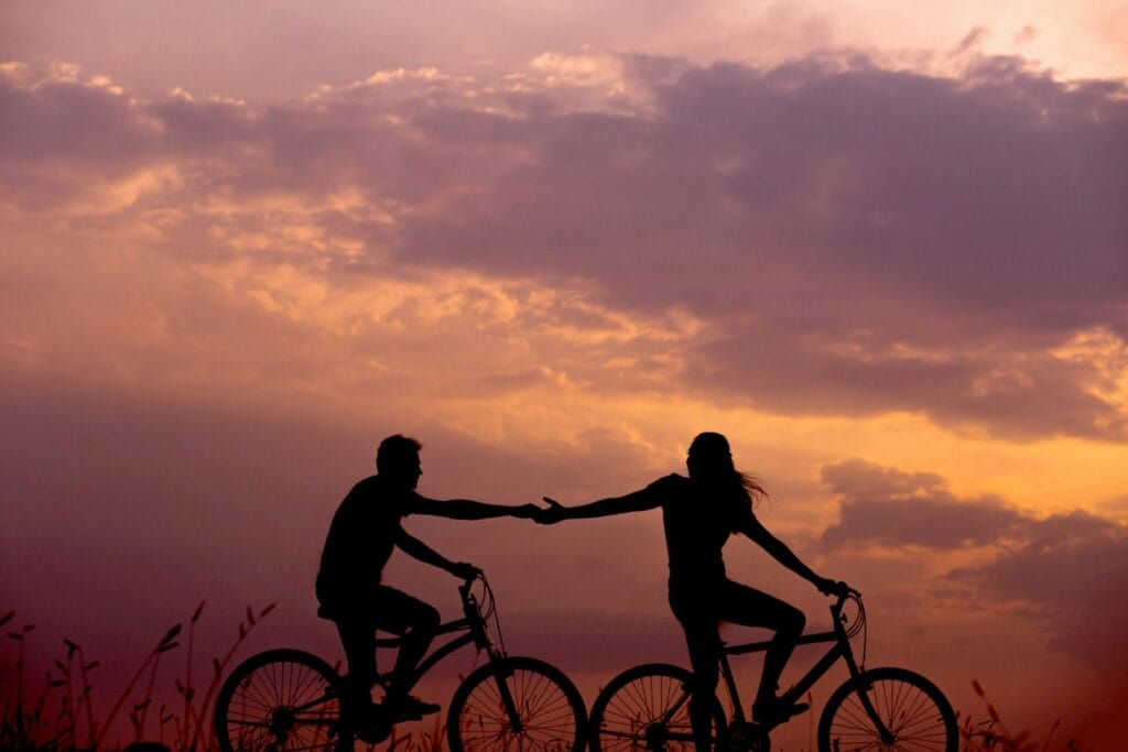 a couple riding bikes silhouetted against the sunset