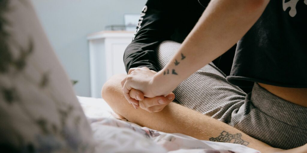 two people sitting on a bed holding hands