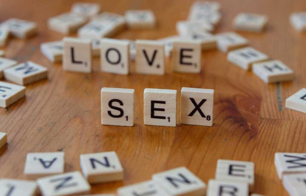 scrabble tiles on a table with the words "love" and "Sex" spelled out