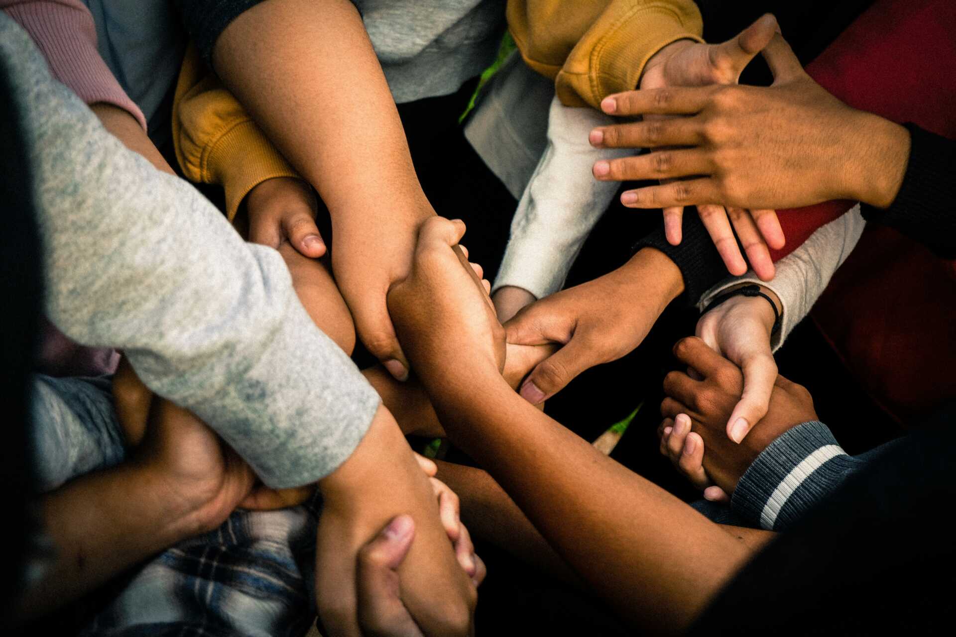 a close up of several sets of hands holding in a circle