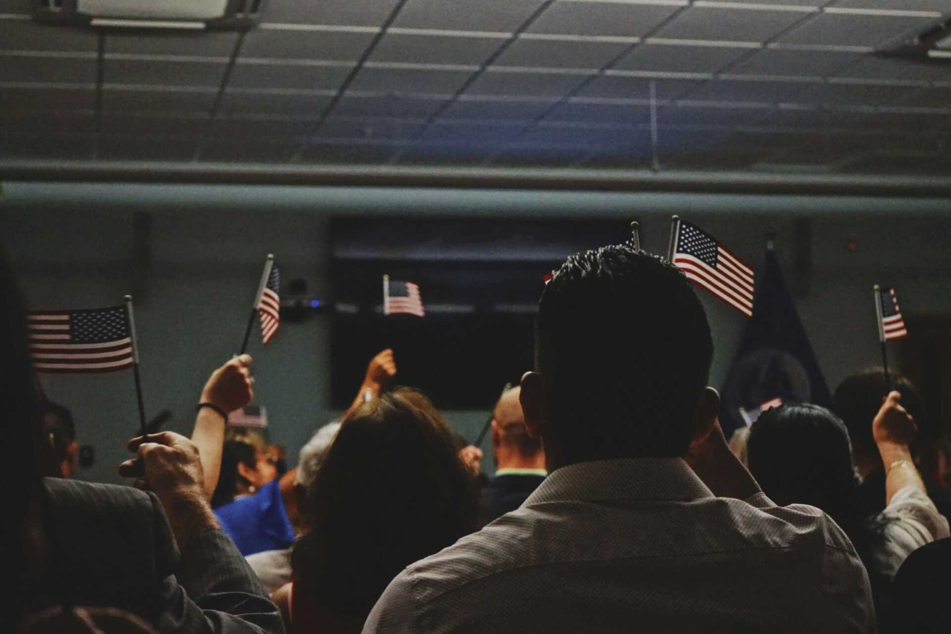 a room of people holding up small American flags