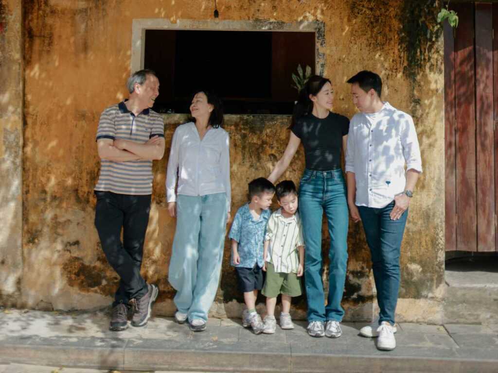 A multigenerational family standing against a wall outside