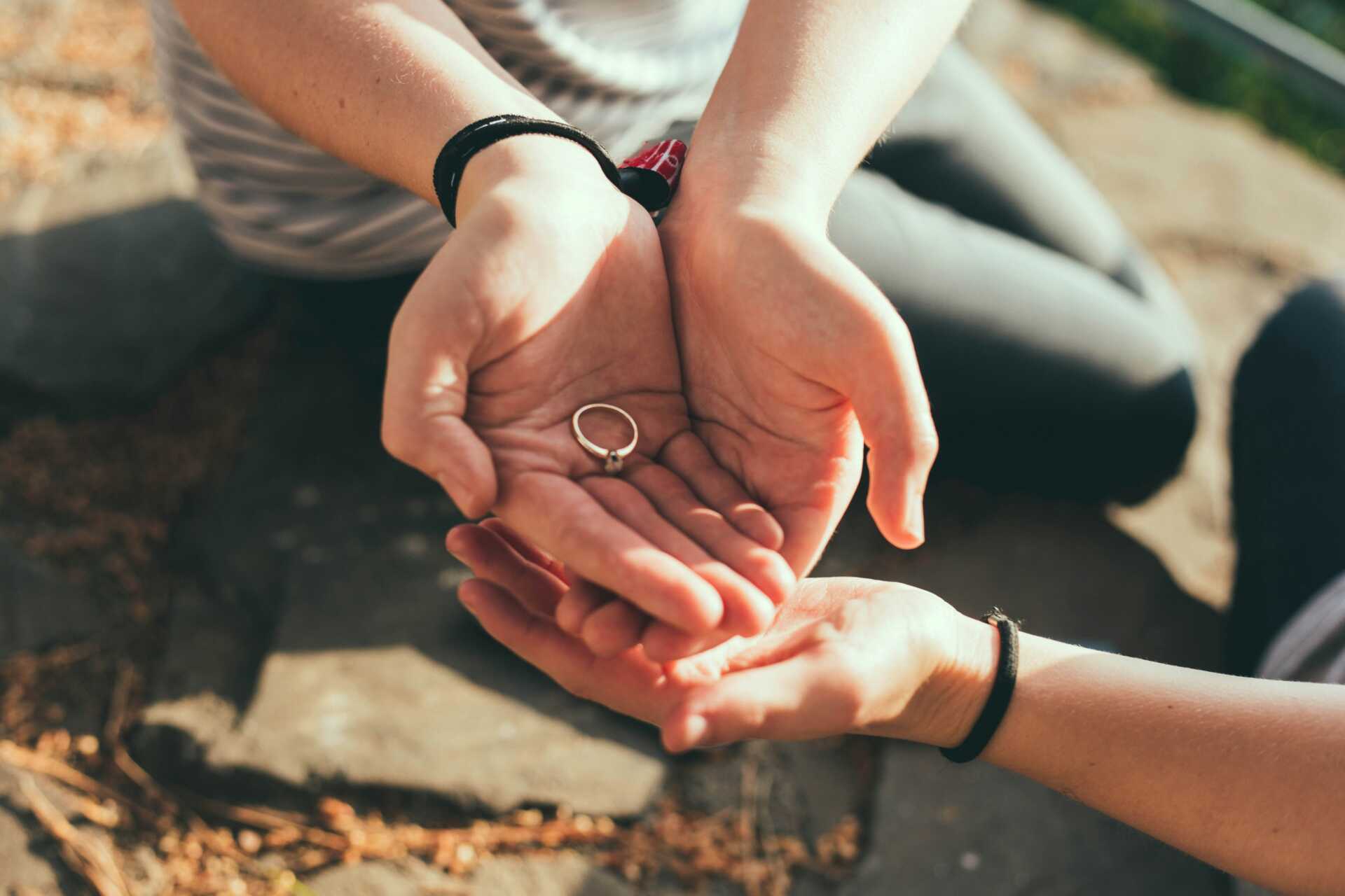 A close up of cupped hands holding an engagement ring