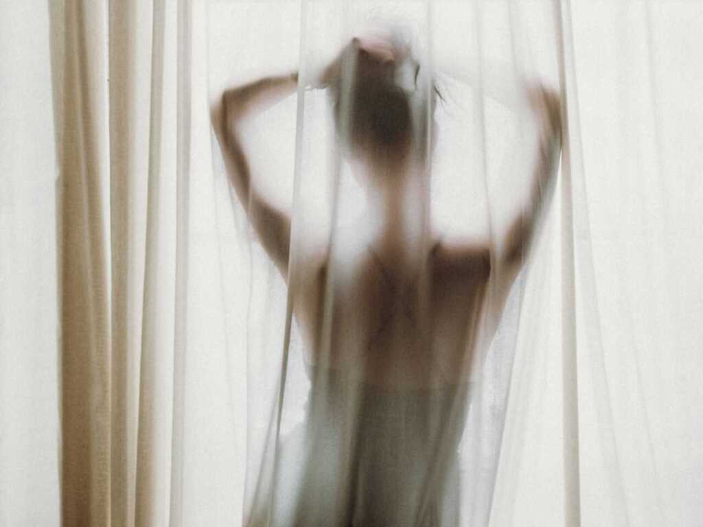 A woman's silhouette behind a gauzy curtain