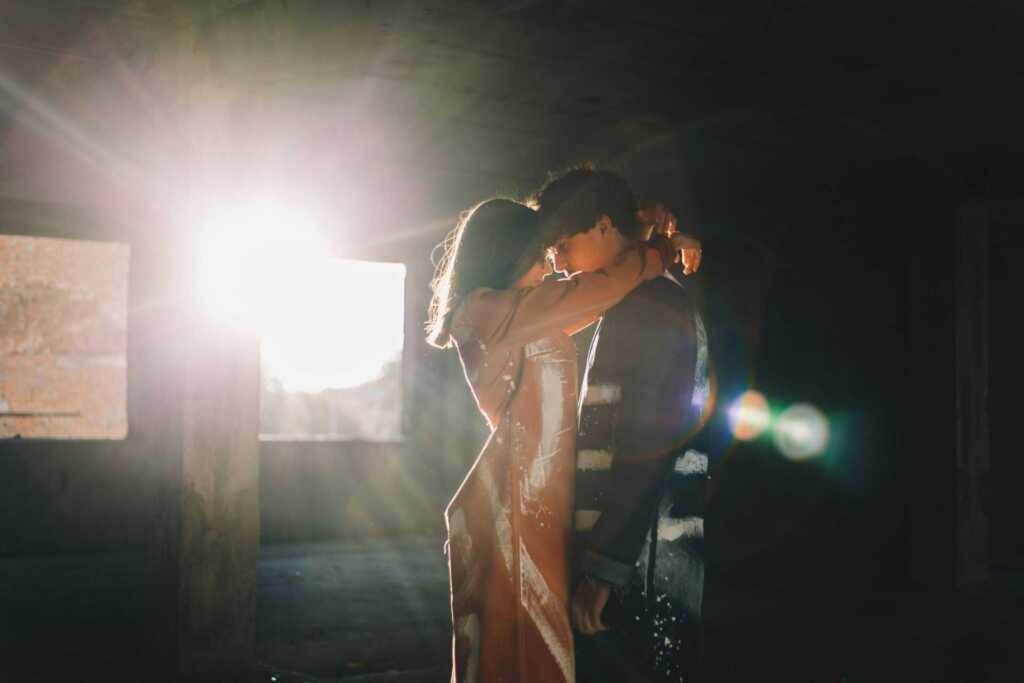 a couple embracing with a flare of sunlight shining through the door behind them