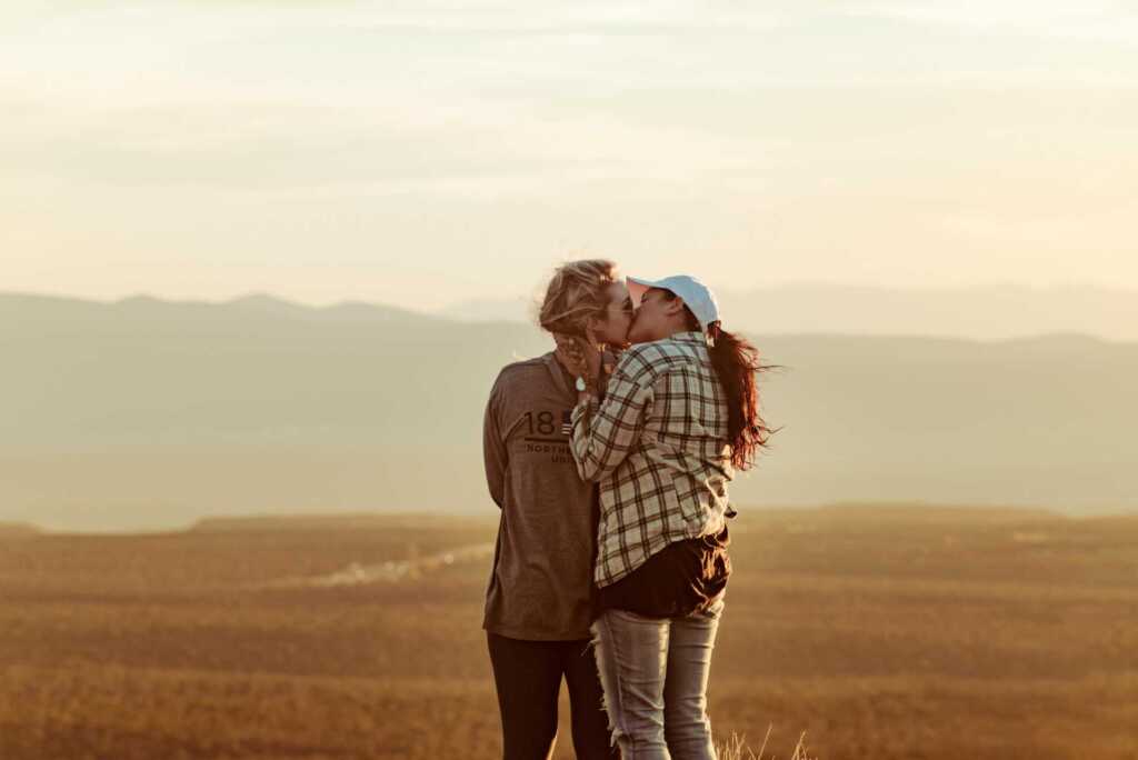 two women kissing in a field