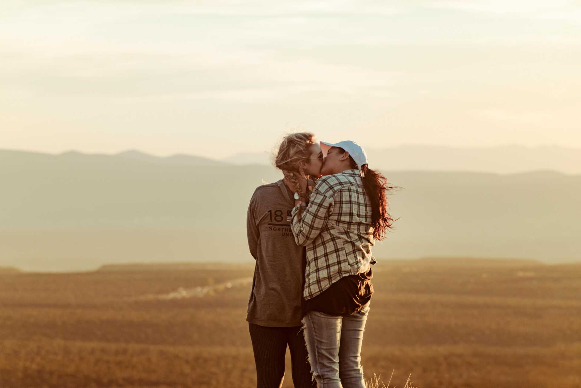 two women kissing in a field