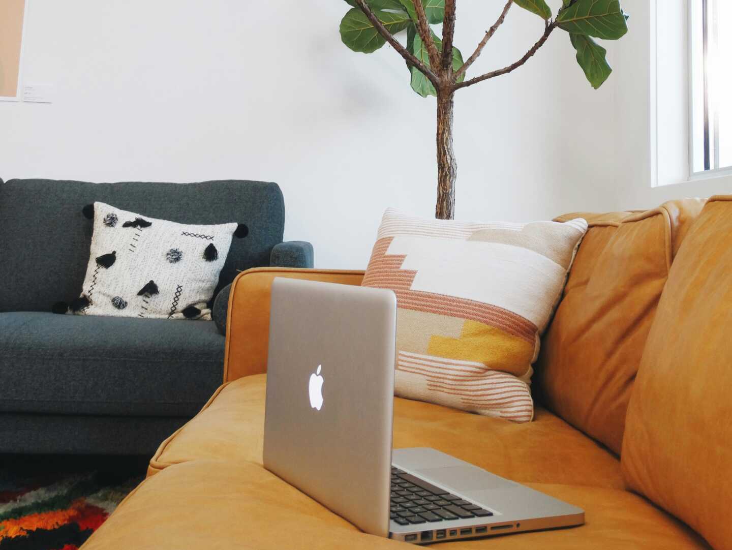 A macbook sitting on an orange couch
