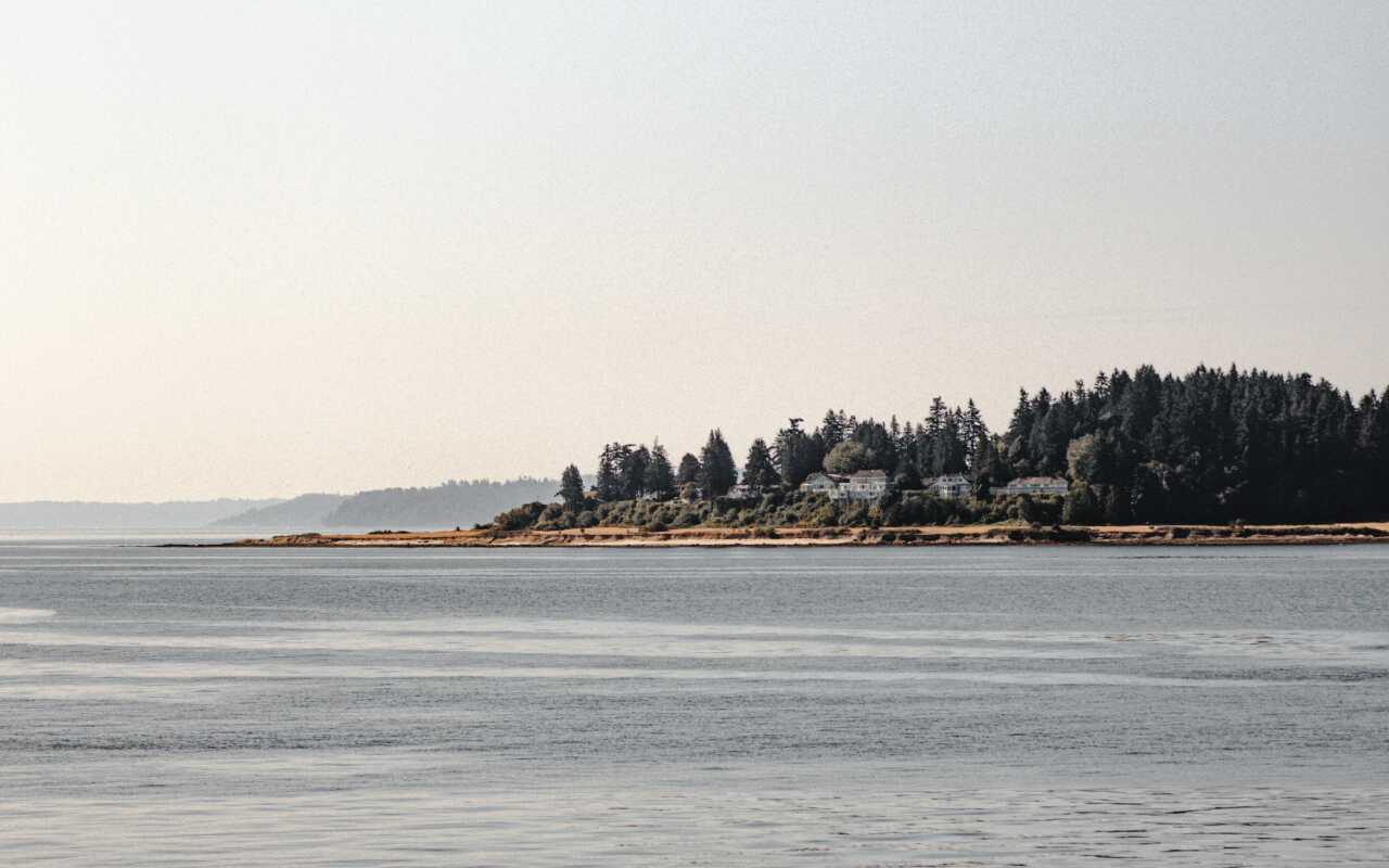 andrew rivera iYbUUvWW2GM unsplash A shoreline in Seattle looking at an island covered in trees