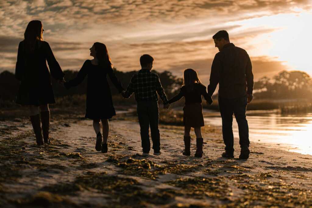 A family shot from behind walking down the beach at sunset