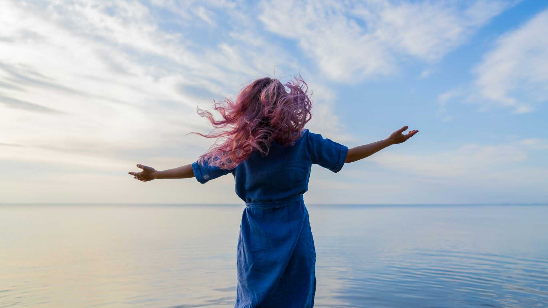 eugene chystiakov 1naYFuwEhDU unsplash A woman standing in front of the ocean with her arms out