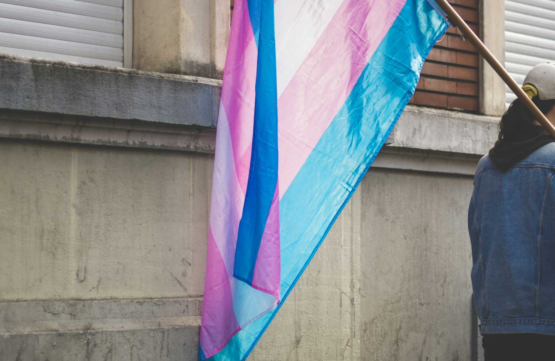 ev LIpXyCKBvtY unsplash a person in a denim jacket holding a transgender pride flag