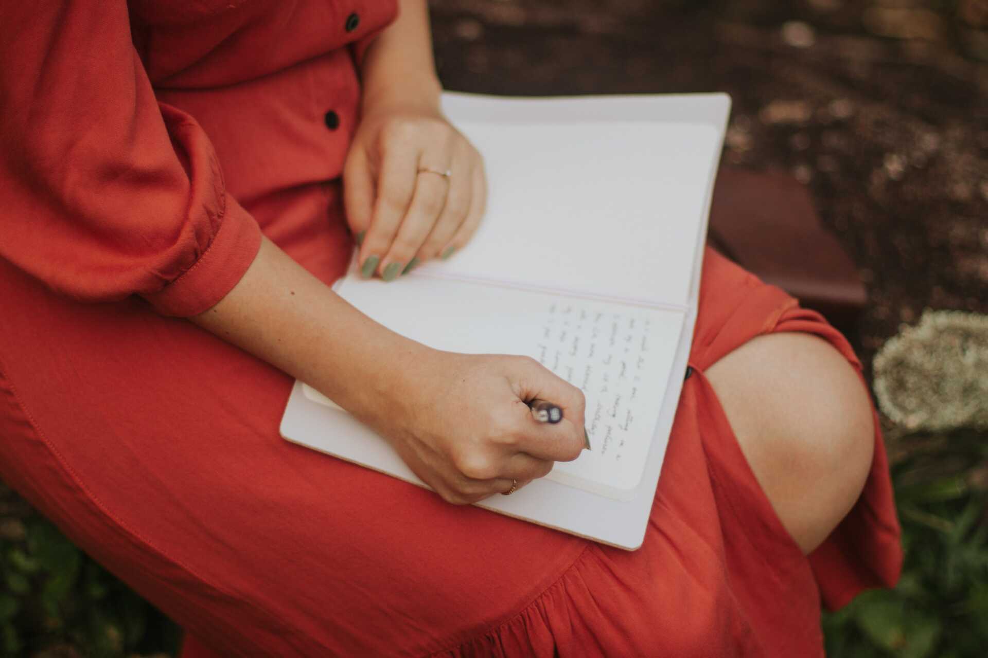A woman in a red dress journaling