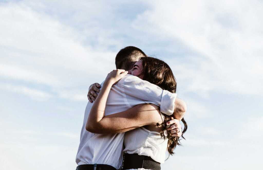 A couple embracing with a cloudy sky in the background
