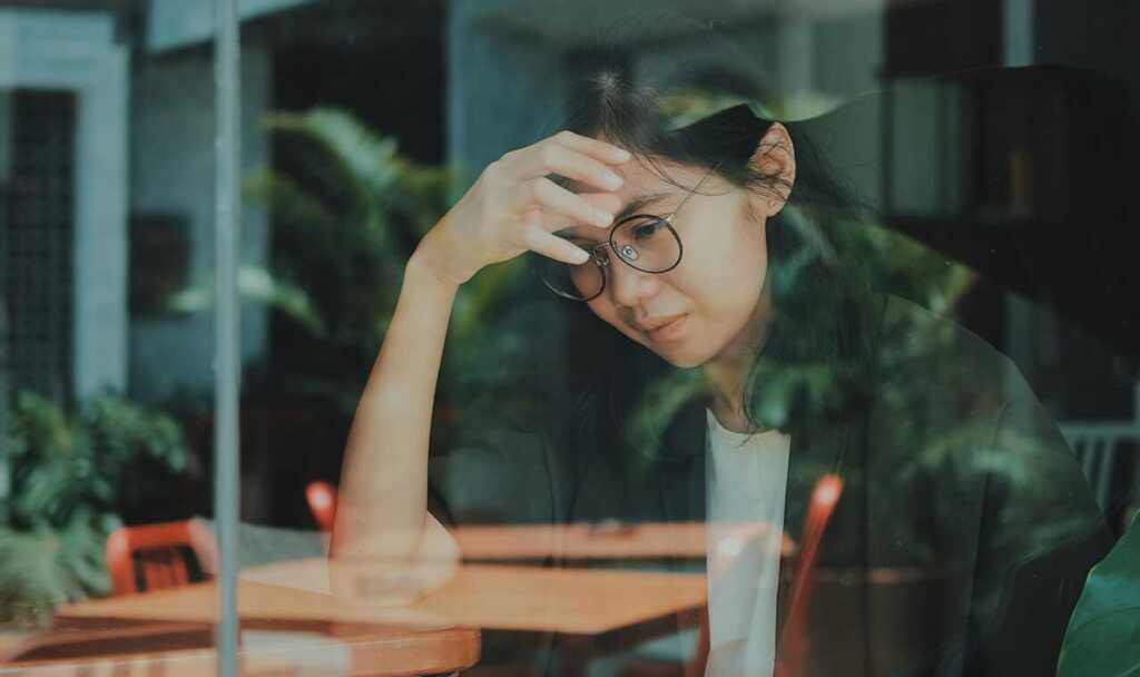 A woman holding a hand to her forehead looking anxious