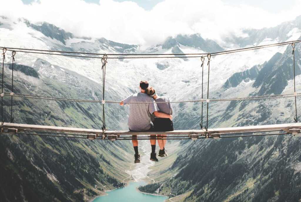 A couple sitting on a bridge looking out over a valley