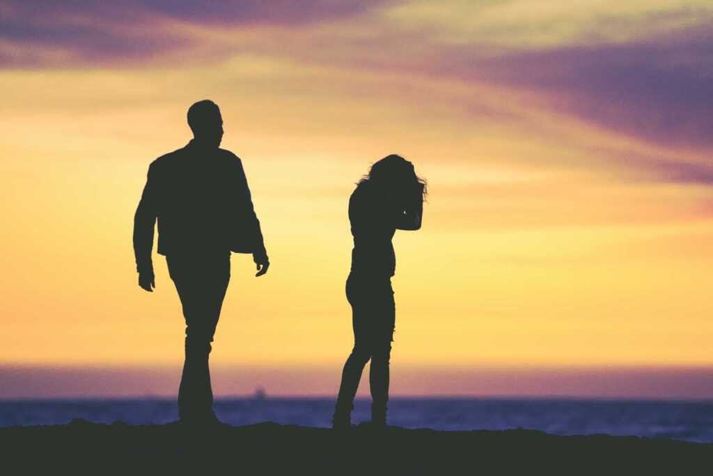 A silhouette of a couple fighting with the sunset behind them