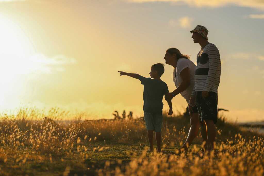 A family outside with a sunset behind them
