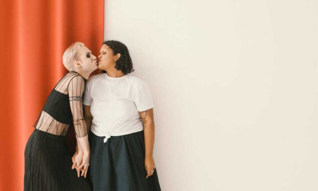 A couple kissing against a cream and orange backdrop