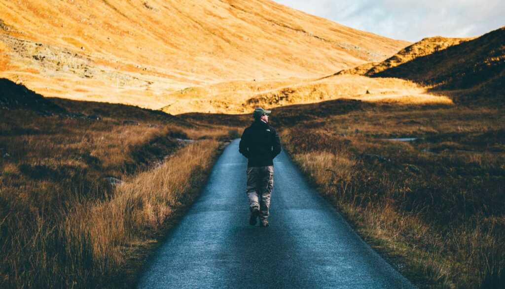 A man walking down a path through the hills
