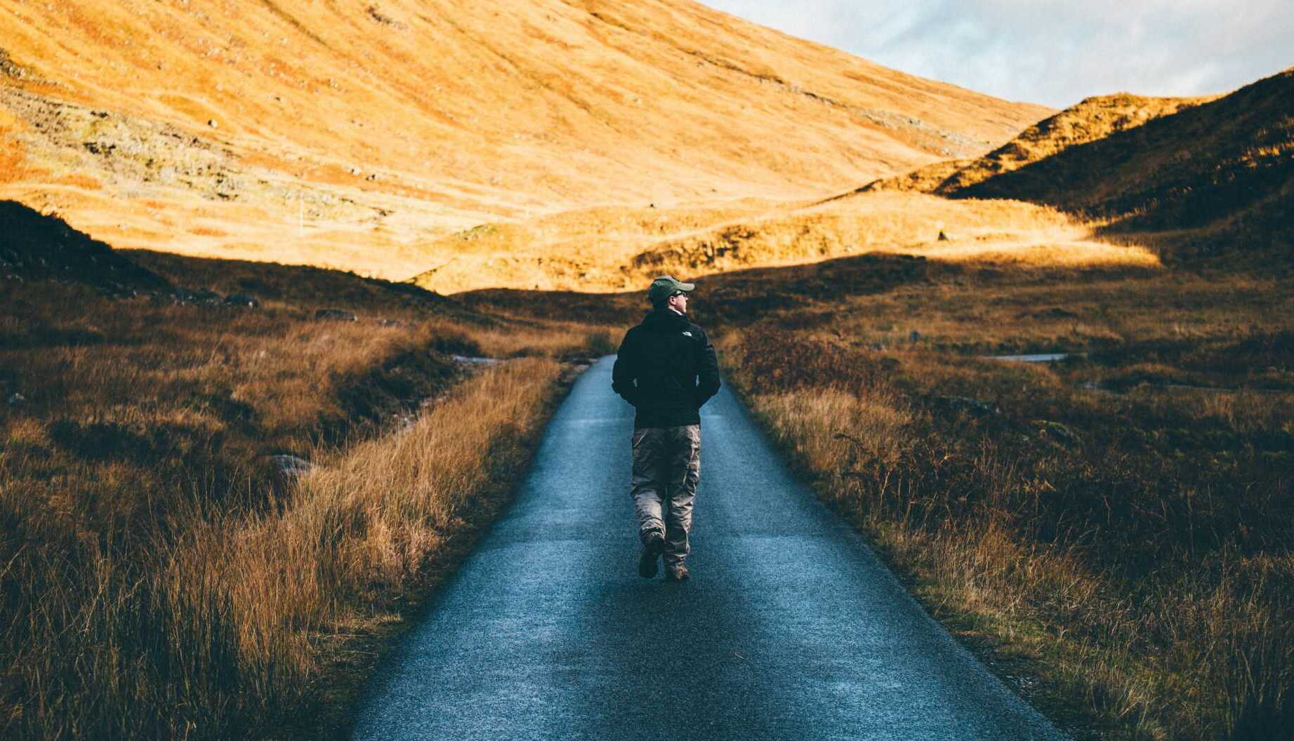 thomas tucker SPcACjrq9ss unsplash A man walking down a path through the hills