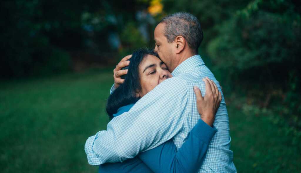 An older couple embracing in a hug outside