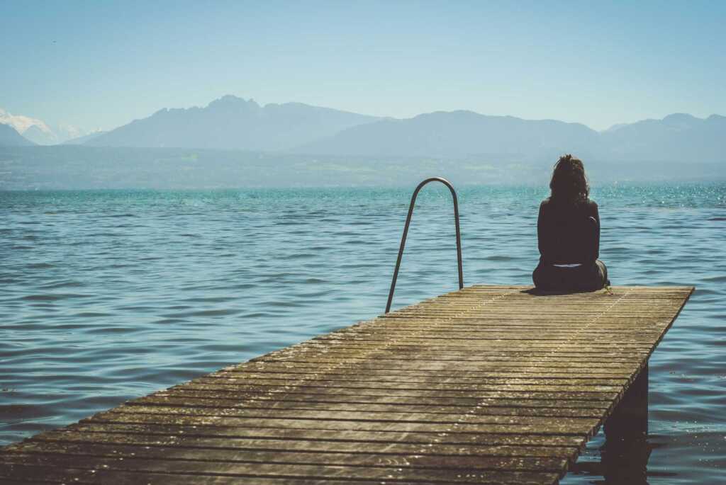 A woman sitting on a dock looking out over the water